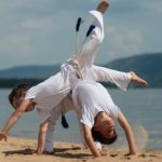 Training of two children on the beach, on the sea: capoeira, sports